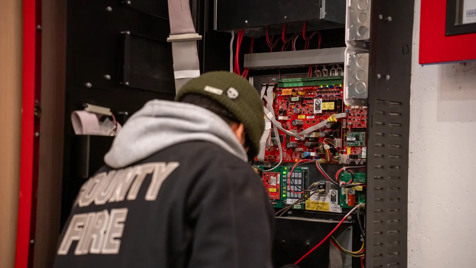 Open fire alarm panel showing circuit boards and field wiring inside