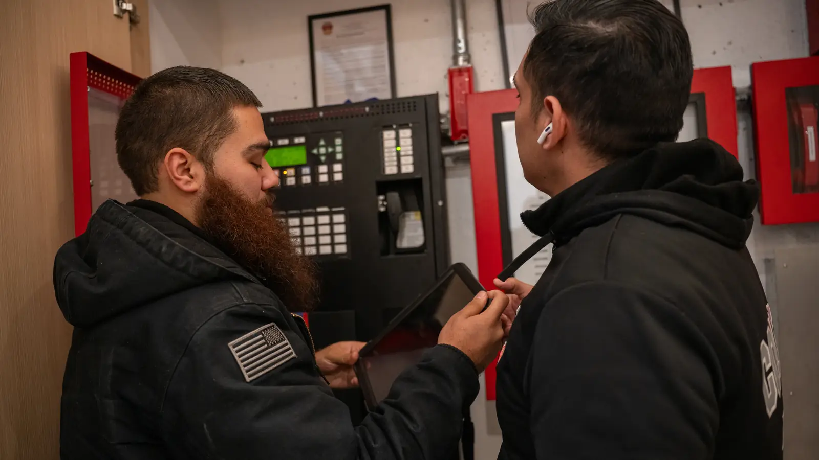 Two County Fire technicians reviewing alarm panel results on a tablet